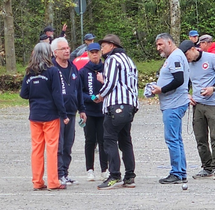 Schiedsrichter Christian Lang im Gespräch mit Spieler*innen von Sindelfingen. Die Spieler des Neulings Gingen hören aufmerksam zu.
